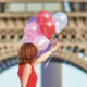 Femme en robe rouge tenant des talons devant la Tour Eifel